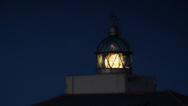 Detail view. Lighthouse with beacon light in the night. Faro Cabo Busto on Asturias coast in Spain. Tourist attraction, place to visit.