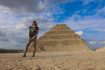 One Tourist Posing with the Step Pyramid of Djoser on the background in the Saqqara necropolis archaeological site, northwest of the city of Memphis, Egypt