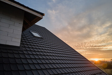 Closeup of house roof top covered with ceramic shingles. Tiled covering of building