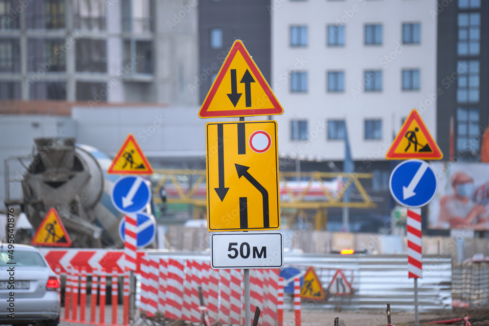 Wall mural roadworks warning traffic signs of construction work on city street and slowly moving cars