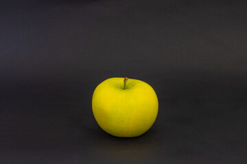 A yellow apple on a black background