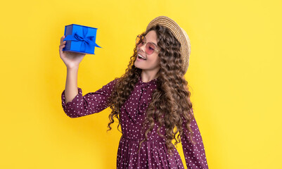 happy child with curly hair hold present box on yellow background