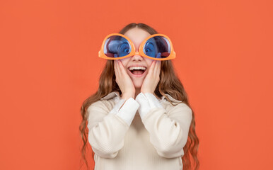 Surprised crazy girl child wearing big funny glasses upside-down brown background