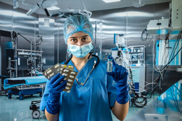 Fototapeta na wymiar young doctor wear blue uniform demonstrating pills and vaccine in the operating room