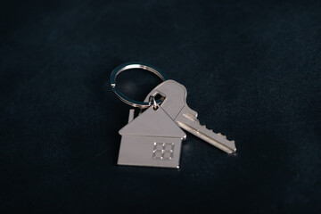 Key with silver house shaped pendant on dark background