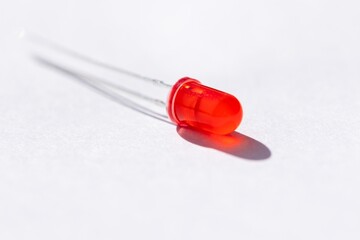 A studio portrait of a single red color LED or colored Light Emitting Diode lying on a white...