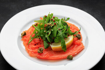 Salmon carpaccio, on a plate, with lemon , on concrete