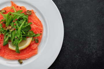 Salmon carpaccio, on a plate, with lemon , on concrete