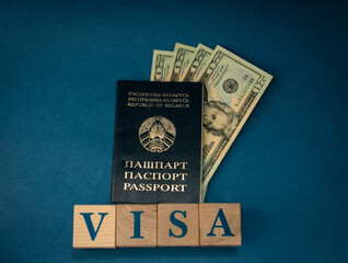 Belarusian passport with dollars on wooden cubes with the inscription VISA on a blue background. Travel, vacation and emigration concept.
