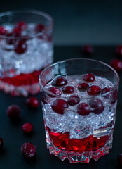 Cranberry cocktail in a low glass with ice on black background