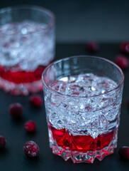 Cranberry cocktail in a low glass with ice on black background