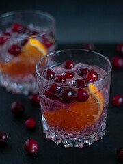 Cranberry cocktail in a low glass with ice on black background