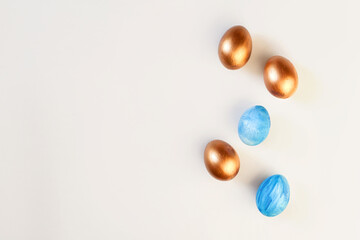 Set of Easter blue and golden color eggs isolated on white background. Stylish trendy frame composition with gold chocolate egg. Flat lay, top view, place for text. Happy egg hunt for kids concept