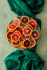 Halves of a blood orange in a plate on a green tablecloth, top view