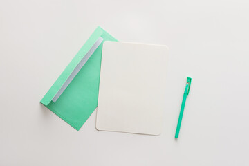 Green mint envelope with blank paper and pen, greeting card or invitation mockup, top view, copy space