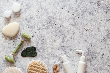 Various cosmetic devices, face and body care products. Jade face roller, stone for massage, facial sponges, soaps and various moisturizers. Copy space, top view, flat lay