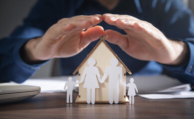 Businessman protect paper cut family and house model. Family insurance