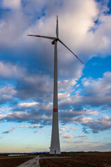 Green renewable energy concept - wind generator turbine in cloudy sky in Germany.