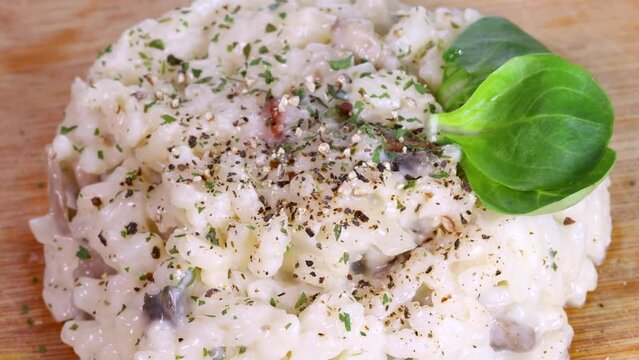 Appetizing risotto rotating on a wooden board, macro shot in 4k of homemade italian food.