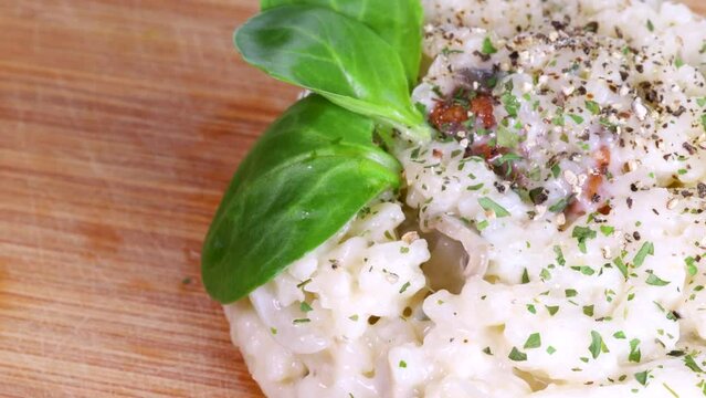 Close up view of beautiful homemade risotto rotating on wood surface, macro shot in 4k.