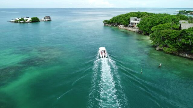 Aerial shot of a boat passing by Rosario Islands houses in Cartagena, Colombia