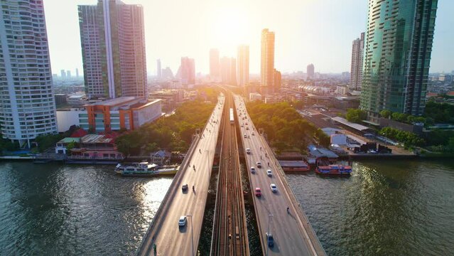4K : Drones fly over the Chao Phraya River. Aerial view over bts skytrain, moving car on bridge, moving boat on river. view of downtown, Flying over Bangkok, Thailand.

