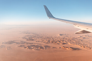 View from the plane on the wing and mountains in the desert of Africa