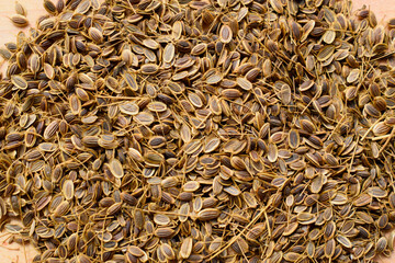 Dill seeds on a wooden surface top view.