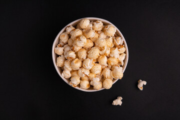 Obraz na płótnie Canvas bucket of caramel popcorn on a black background top view. The concept of a banner or advertising for a cinema. Place for text