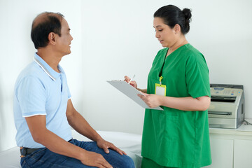 Nurse filling medical history when asking senior patient for complains