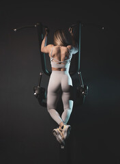 A strong woman doing pull-ups on a back machine.natural bodybuilding concept