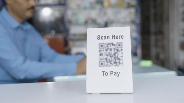 Handheld shot of scan here to pay sign board on table at medical retail store - concept of online or digital payment, cashless small business and technology