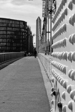 Vertical Shot Of A Narrow Path With Walking People, Grayscale Image