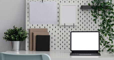 Creative workspace, mockup blank white screen digital tablet with keyboard and supplies on wooden table, copy space.