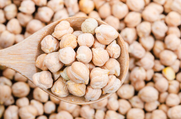 Uncooked chickpeas on wooden scoop.