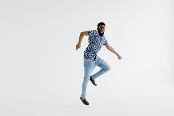 Portrait of a cheerful afro american man in headphones jumping isolated on a white background