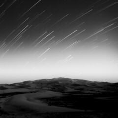 Grayscale of a star trail over the desert