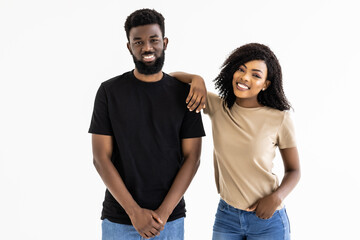 Young couple in jeans and white tops smiling at camera on white background