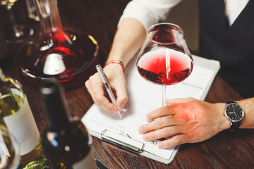 Sommelier writes on clipboard describing red wine at table