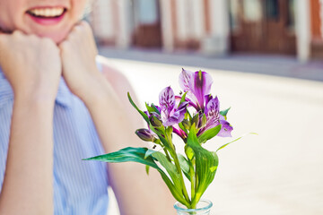 Young smiling woman and purple flowers close-up.