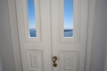 A typical  white traditional door, the blue sky , the aegean sea and the volcano of Santorini in the background