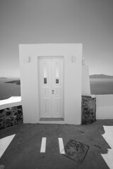 Typical design white decoration door next to an alley with a breathtaking view the aegean sea in Santorini in black and white