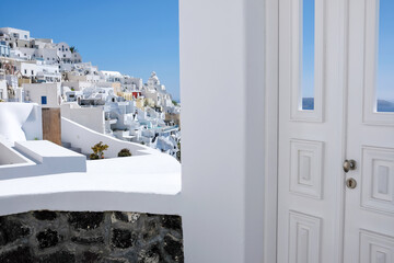 Typical design white decoration door next to an alley with a breathtaking view of the village Fira and the aegean sea in Santorini - obrazy, fototapety, plakaty
