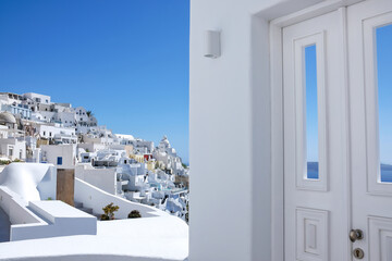 Typical design white decoration door next to an alley with a breathtaking view of the volcano and the aegean sea in Fira Santorini
