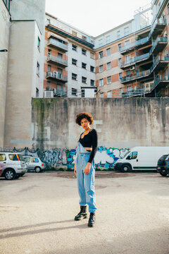 Young afro curly hair woman posing outdoor carefree cool attitude