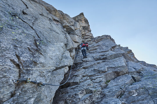 Low angle shot of a male climbing a cliff during the day in Austria