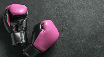 Pink boxing gloves on a black background. Fight for women rights or against breast cancer. Copy...