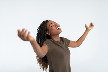 Beautiful young african woman celebrates with her hands in the air on white background