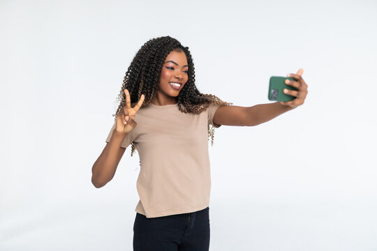 Young attractive african woman is taking a selfie with her cellphone isolated over white background