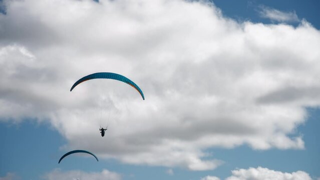 Parachutist is paragliding against the cloudy sky background. Slow motion. Extreme sports activities concept. 